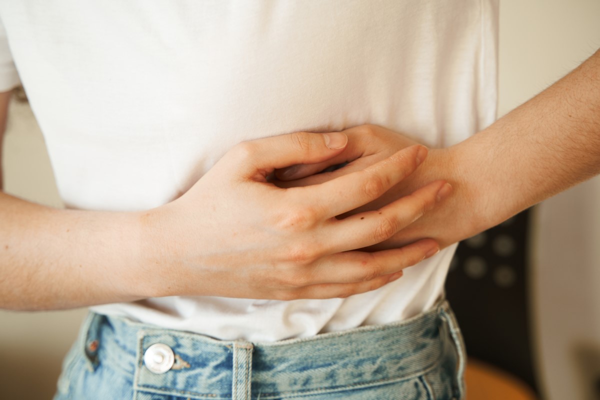 De vrouw houdt haar zere zij vast met haar handen, heeft buikpijn en andere gezondheidsproblemen die kunnen wijzen op een darmobstructie.