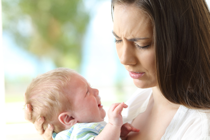 Een huilende baby wordt in de armen van de moeder gehouden