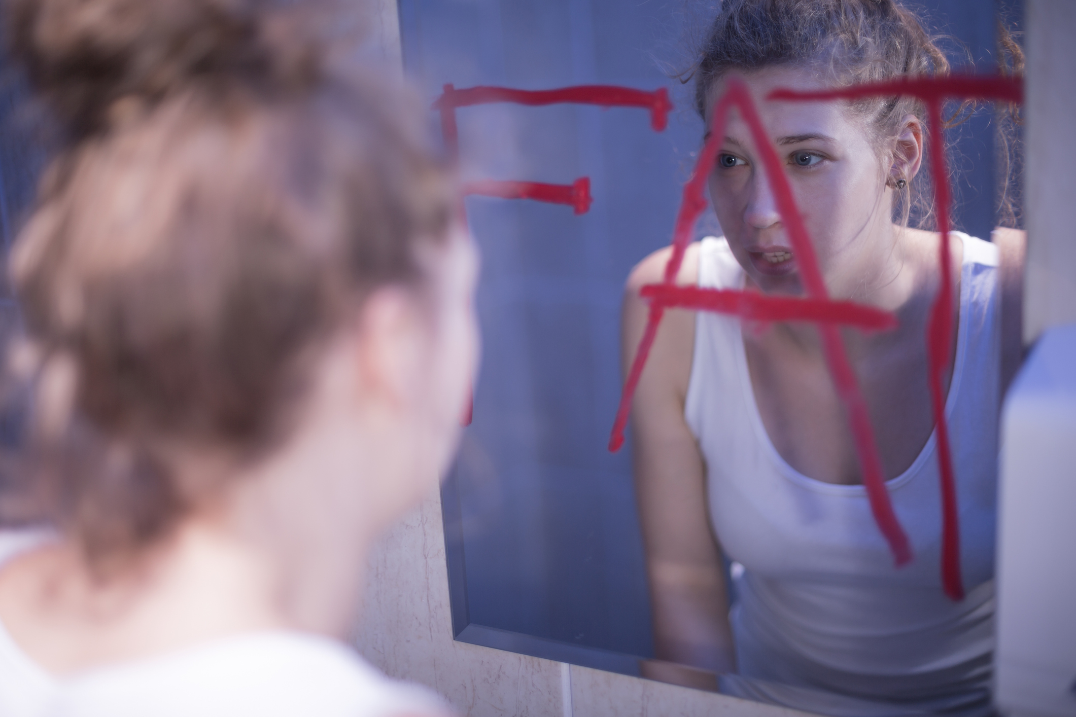 Een jonge vrouw die denkt dat ze dik is als ze in de spiegel kijkt.