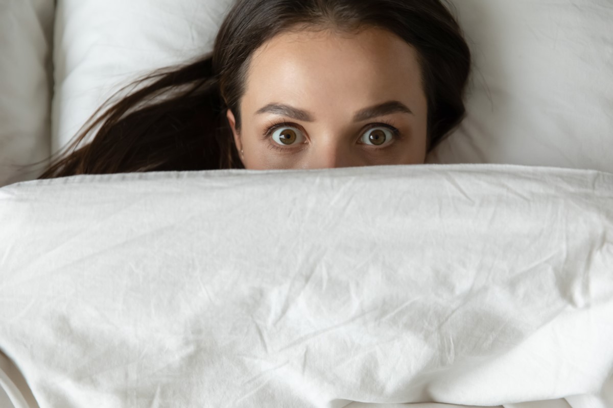 Een nachtmerrie en een vrouw die doodsbang in bed ligt