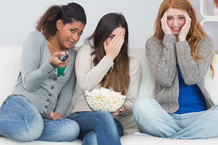 Drie meisjes zijn bang, kijken naar enge film, popcorn in een kom