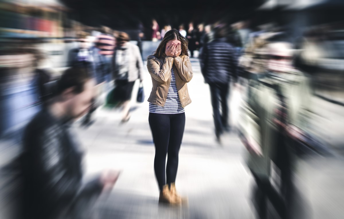 Verwarde vrouw staat in een menigte mensen, heeft een mentaal probleem, overdreven gevoeligheid voor licht en geluid, lawaai