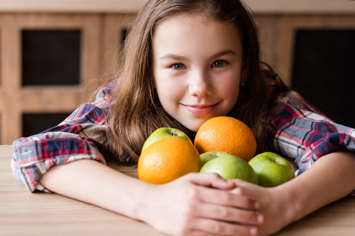 Vitamine C, in fruit, een kind met sinaasappels en appels in zijn armen