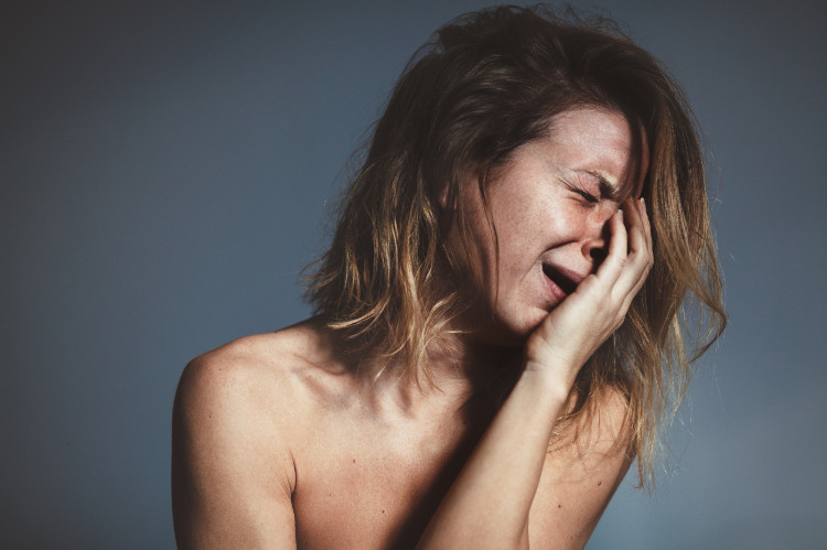 een huilende vrouw houdt haar gezicht vast met haar hand