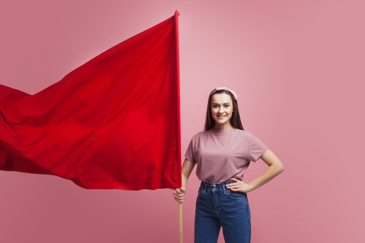 Een vrouw houdt een grote rode vlag vast als waarschuwing.