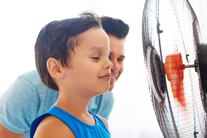 Een jongen en zijn vader staan voor een ventilator