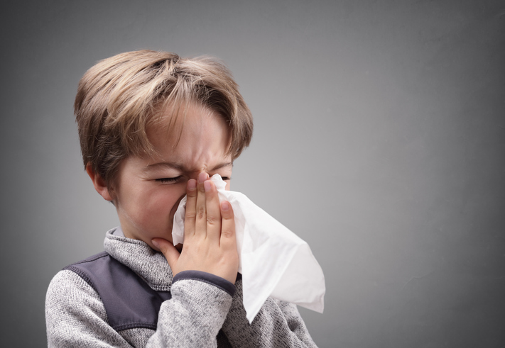 De jongen snuit zijn neus, slijm, in een hygiënische zakdoek