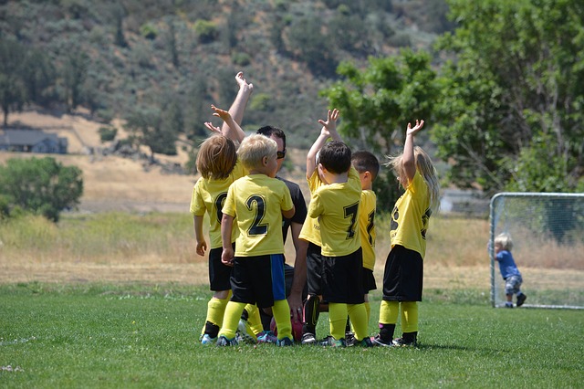 Kinderen in gele shirts op het voetbalveld. Genietend in een groep met hun coach.