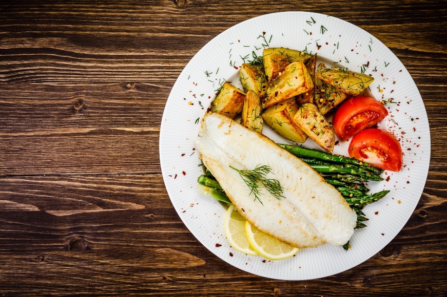 Voorbeeld van een diner: gegrilde vis met asperges, geroosterde aardappelen, kruiden en verse groenten.