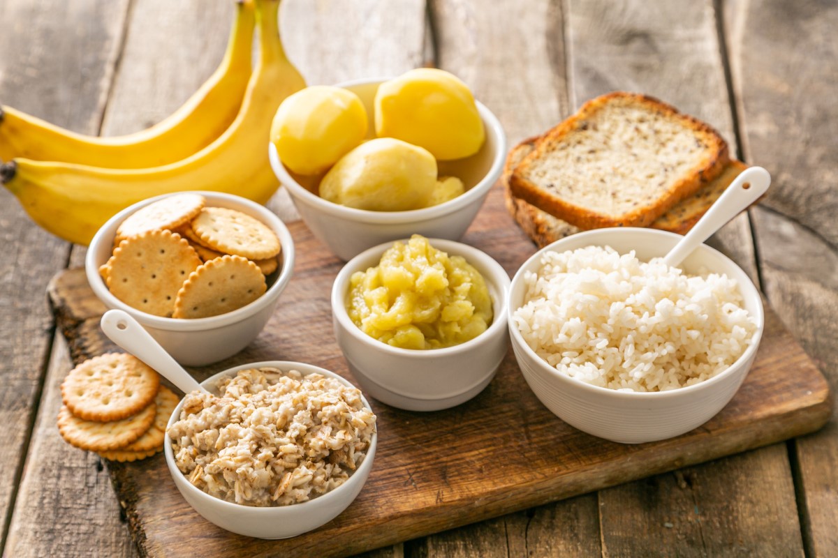 Voorbeeld van een geschikt dieet voor acute diarree - rijst, aardappelen, bananen, crackers, in kommen en op een houten snijplank.