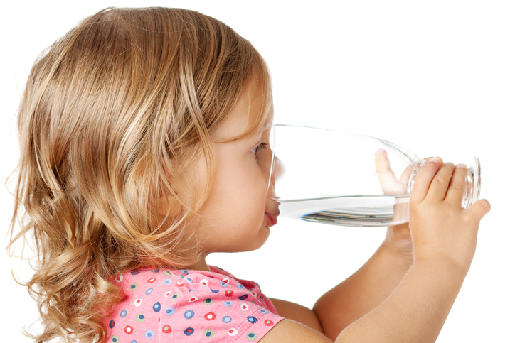 Een klein meisje drinkt schoon water uit een glas