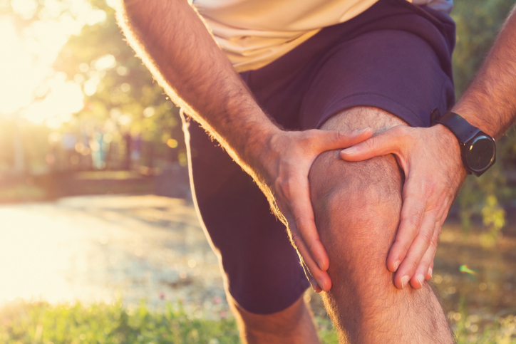 mannelijke atleet houdt zijn pijnlijke knie vast