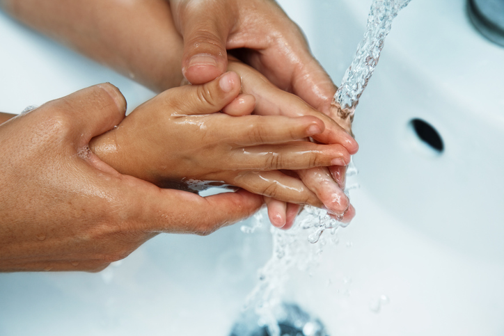 moederhanden boven de gootsteen babyhandjes wassen onder stromend water