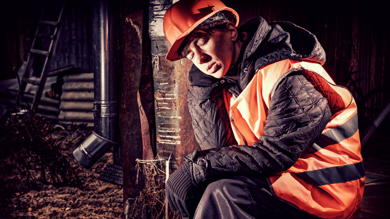 slapende man aan het werk met rode helm en reflecterend vest