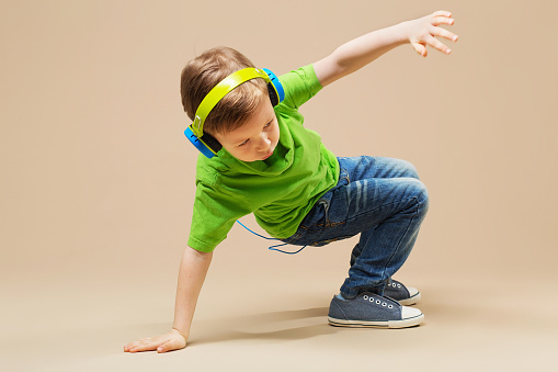 Een kind in een groen shirt met een koptelefoon op doet een breakdance