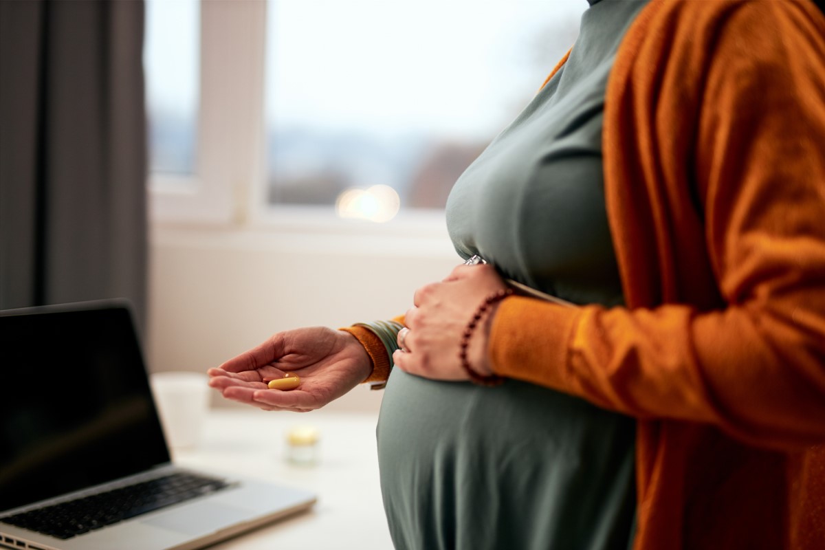 Een zwangere vrouw heeft medicijnen in haar hand en weet niet welke veilig zijn.