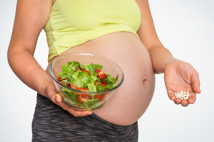 Zwangere vrouw met salade en pillen