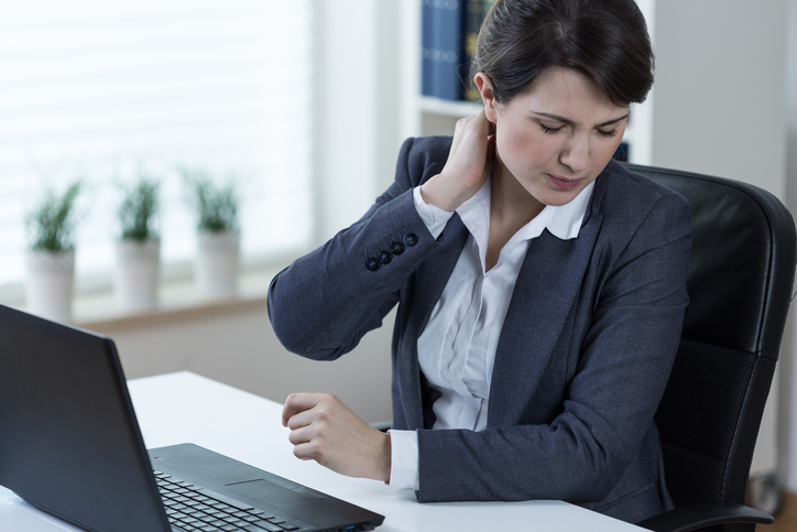 Een vrouw heeft pijn in de halswervelkolom door langdurig computerwerk en langdurig zitten