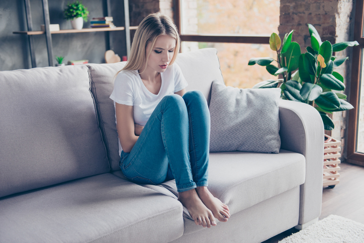 de vrouw zit met pijn op de bank 