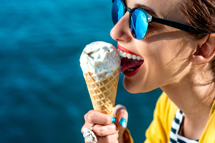 vrouw met zonnebril die ijs likt naast het water