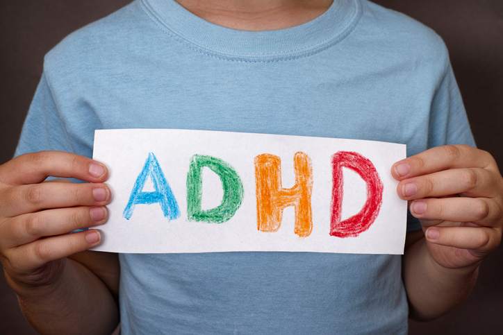 Een jongen houdt een bord vast met een kleurrijk ADHD-teken erop