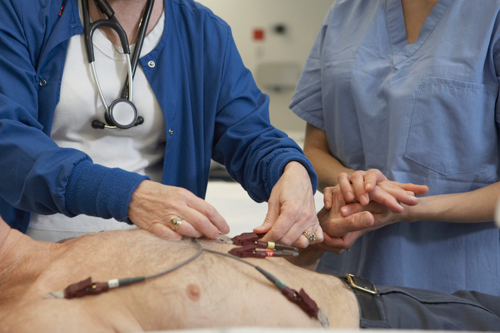 EKG-onderzoek van de man, elektroden op zijn borst, twee artsen onderzoeken hem