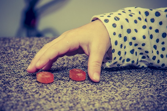 Een kinderhand, twee rode snoepjes, slechte eetgewoonten