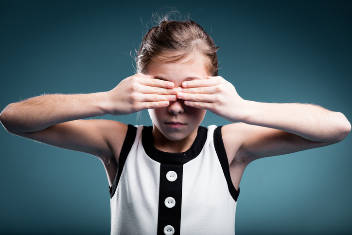 een jong meisje bedekt haar ogen als teken van blindheid