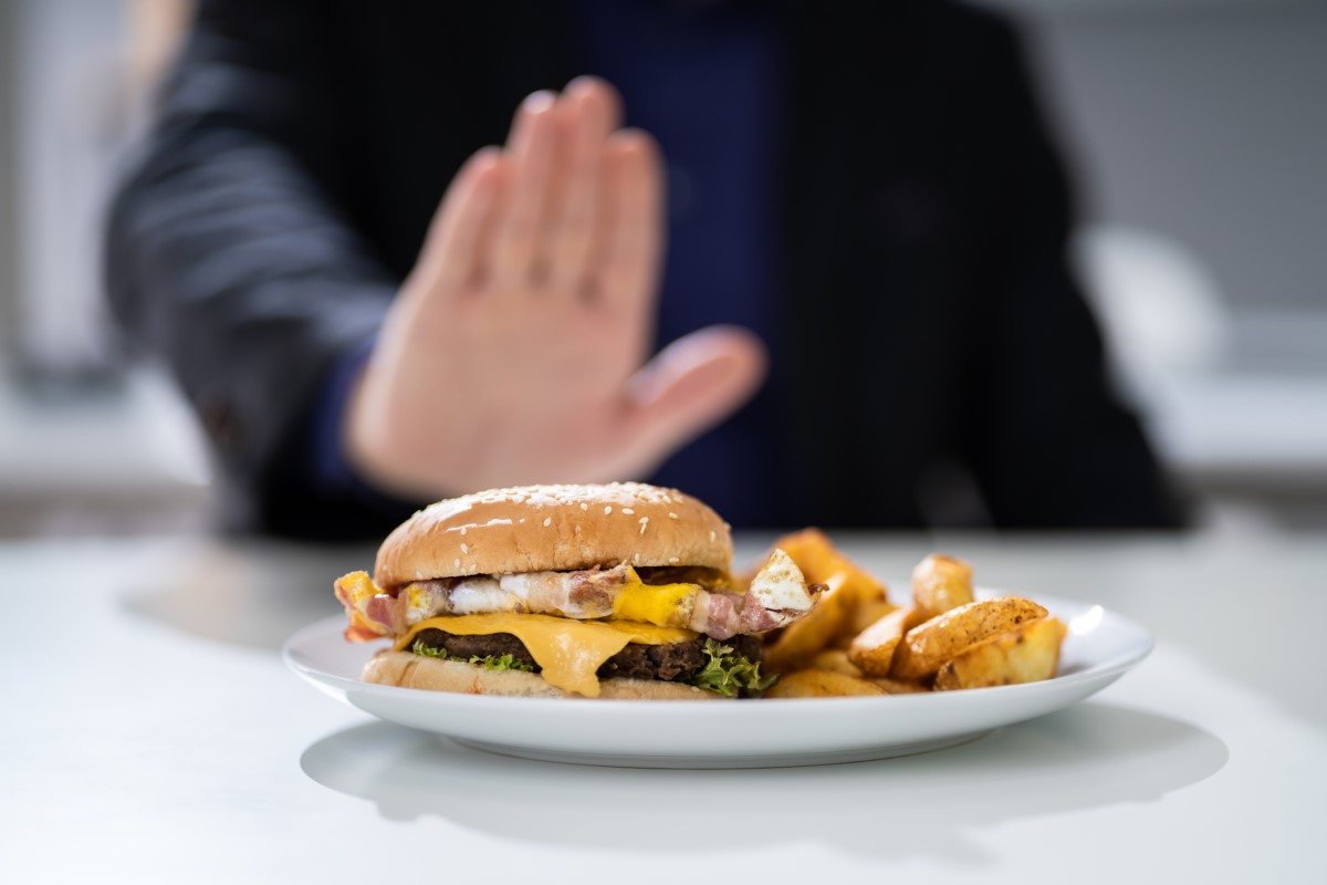 Ongepast voedsel als oorzaak van brandend maagzuur - een hamburger op een bord dat een man weigert