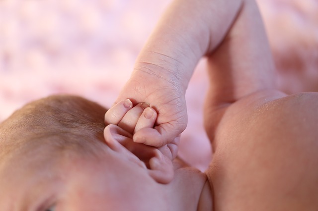 een klein kind (peuter) houdt zijn oor vast met zijn hand