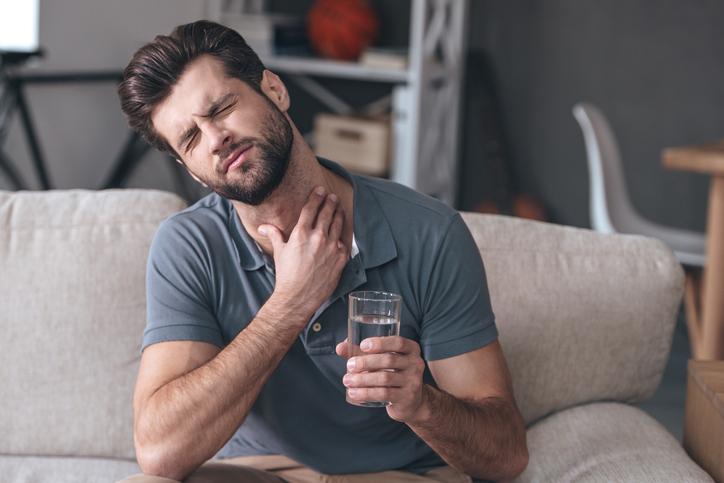 Man heeft keelpijn - verergerd door water drinken