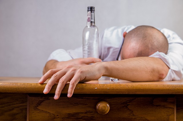 Alcoholisme is de oorzaak van stemmingsstoornissen, een man ligt op een tafel met een lege fles alcohol, een alcoholist