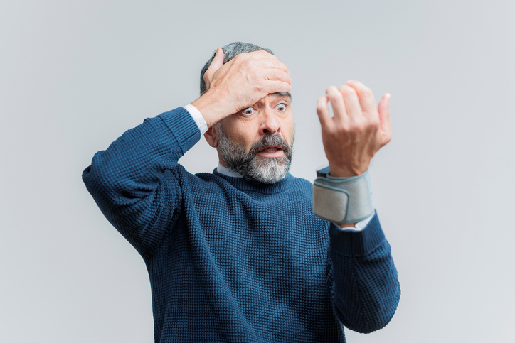 Een oudere man meet zijn bloeddruk aan zijn pols en is ontzet bij het zien van een bloeddrukmeter