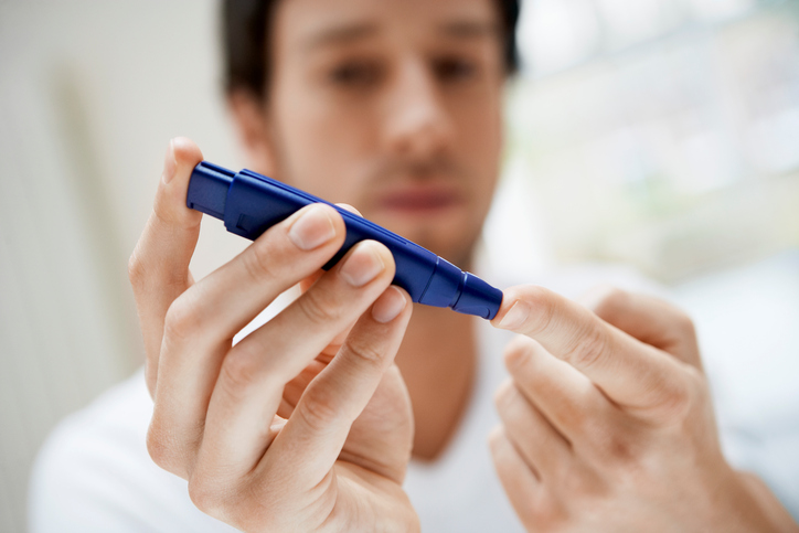 De man heeft diabetes, hij meet zijn bloedsuiker met een glucometer