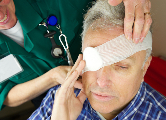 een grijze man heeft een ingezwachteld oog, bijvoorbeeld na een ongeluk, een paramedicus behandelt hem