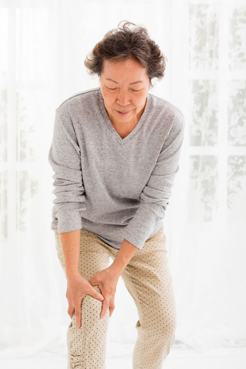 Een oudere dame heeft kniepijn door gonartrose, ze houdt haar knie vast met haar handen