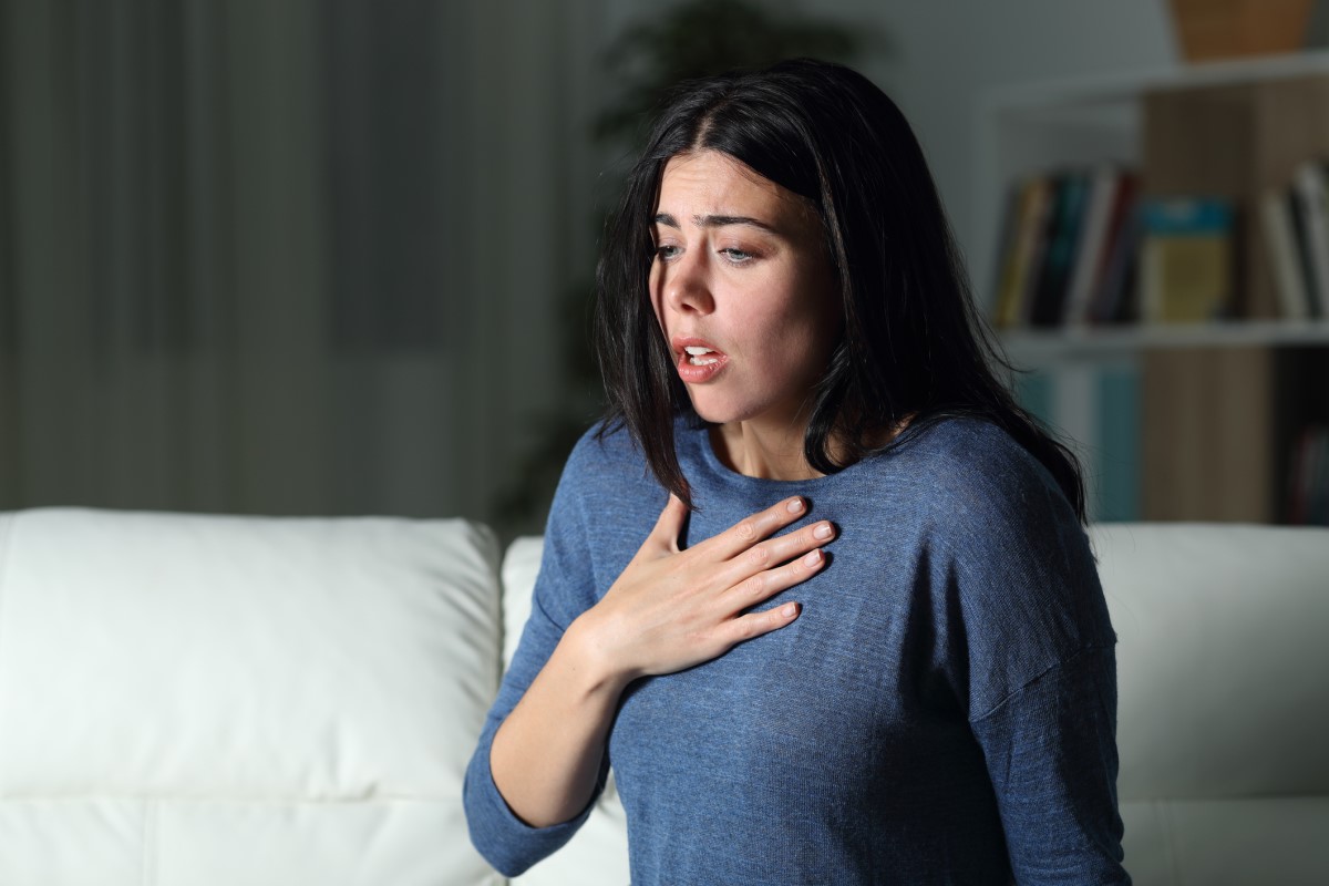 Vrouw krijgt paniekaanval, angst, gaat rechtop zitten en houdt haar borst vast