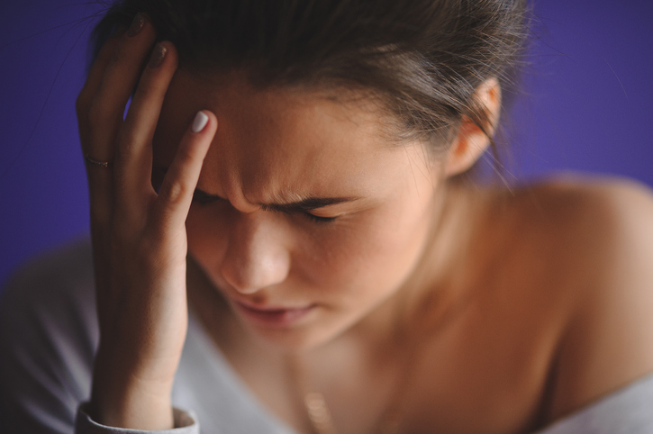 Vrouw houdt haar hoofd vast, heeft hoofdpijn