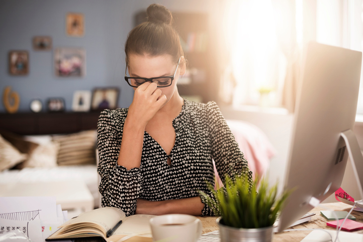 Vrouw zittend achter computer, moe, ogen doen pijn, lang werk