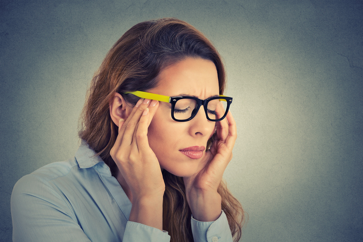 vrouw met hoofdpijn en oogpijn, gele bril, migraine