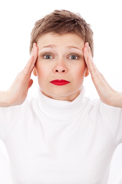 de vrouw houdt haar hoofd vast met haar handen, haar hoofd doet pijn, haar lippen zijn rood geschilderd