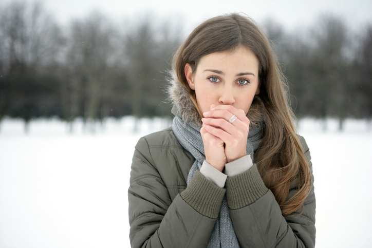 Een vrouw verwarmt haar koude ledematen met haar adem, het sneeuwt buiten, koud, koud