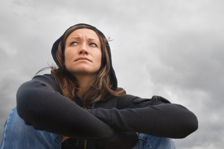 Zittende vrouw, sombere stemming, bewolkt weer