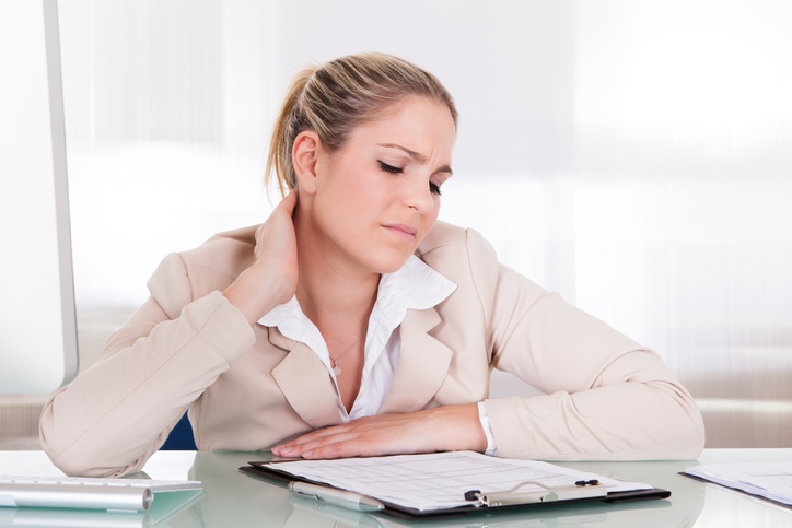 Een vrouw heeft stijve spieren van de halswervelkolom, nek, bij langdurig zitten, zittend werk en werkstress